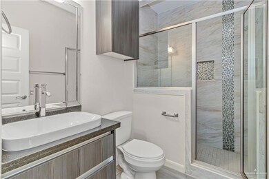 Bathroom featuring a shower with shower door, toilet, and vanity