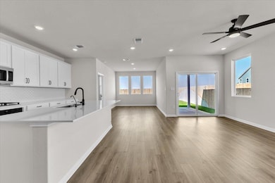 Kitchen with open floor plan, white cabinets, a center island with sink, backsplash, and plenty of natural light