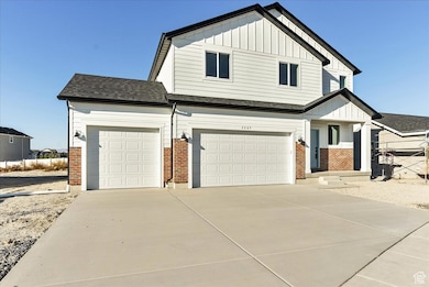 View of front of property with board and batten siding, brick siding, and driveway