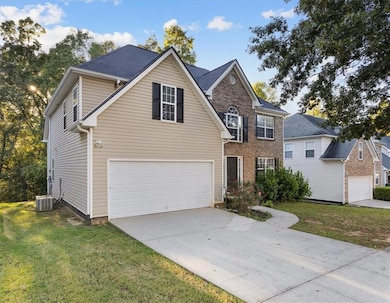 Traditional-style home with an attached garage, a front yard, and driveway