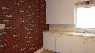 Kitchen cabinets and sink and faux brick wall pape