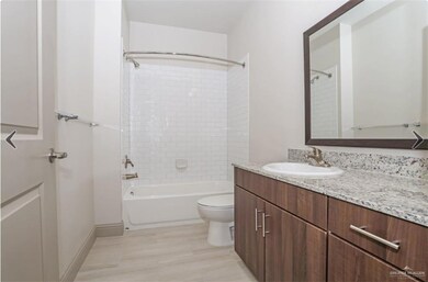 Full bathroom featuring tiled shower / bath combo, vanity, toilet, and hardwood / wood-style floors