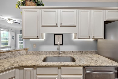 Kitchen with light stone counters, ornamental molding, stainless steel appliances, and a ceiling fan