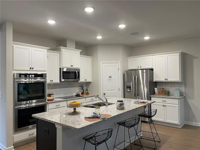 Kitchen with tasteful backsplash, dark wood finished floors, light stone countertops, a kitchen bar, and recessed lighting