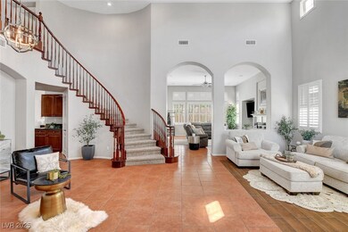 Living area with ceiling fan, stairway, arched wal
