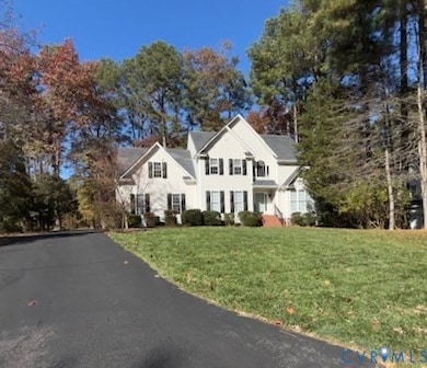 Traditional home with a front lawn and view of wooded area