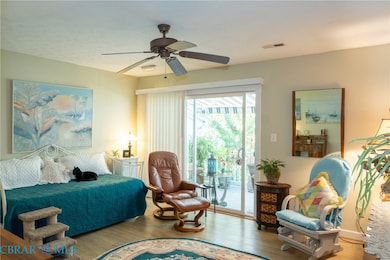 Bedroom with wood finished floors, a ceiling fan, and access to exterior