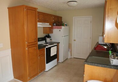 The eat-in kitchen has plenty of cabinets. The door on the end is the pantry / utility closet.