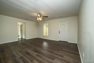 Spare room with a textured ceiling, dark wood-style floors, and a ceiling fan