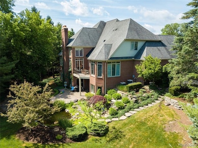 Rear view of house with a patio area, brick siding, a chimney, and roof with shingles