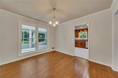 Empty room with light wood finished floors, a chandelier, ornamental molding, and a textured ceiling