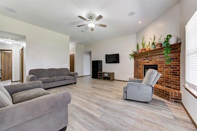 Living area with a ceiling fan, light wood-type flooring, a brick fireplace, and baseboards