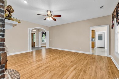 Unfurnished living room with ceiling fan, arched walkways, light wood-style floors, baseboards, and ornate columns
