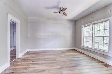 Empty room with a ceiling fan and light wood-style flooring