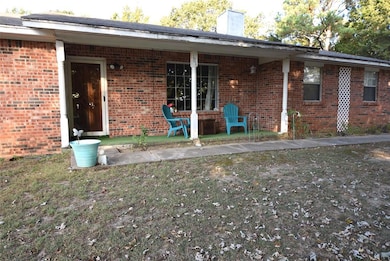 Front of house featuring a chimney, brick siding, and a porch
