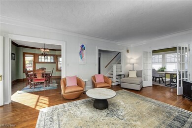 Living room featuring crown molding, dark hardwood / wood-style floors, a chandelier, and a healthy amount of sunlight with new paint (2023)