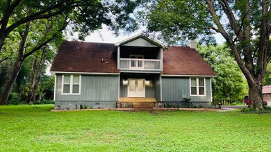 View of front of property with crawl space, a balcony, a chimney, and a front lawn