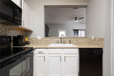 Kitchen featuring black appliances, a sink, light