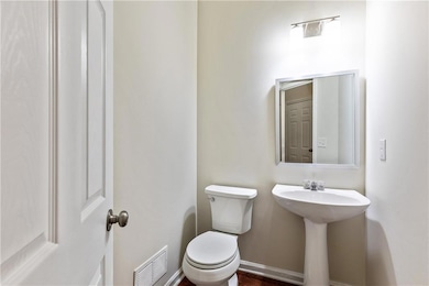 Half bath with toilet, a sink, visible vents, and 