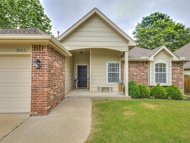 View of front facade featuring an attached garage, a shingled roof, brick siding, and a front yard