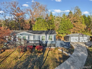 View of front of property featuring an outbuilding, a garage, a wooden deck, crawl space, and a front yard