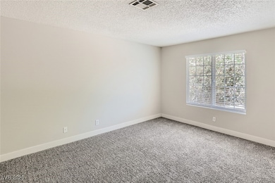 Unfurnished room featuring carpet and a textured c