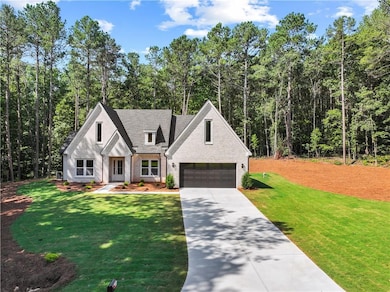 Modern inspired farmhouse with concrete driveway, a garage, a front yard, brick siding, and a forest view