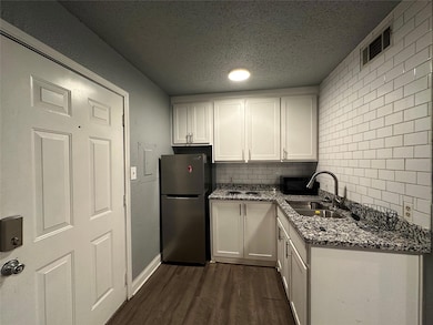 Kitchen featuring a textured ceiling, a sink, whit