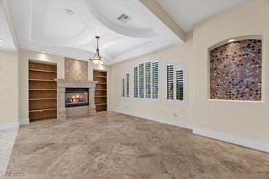 Elegant formal living room featuring a fireplace, built in features, and a tray ceiling