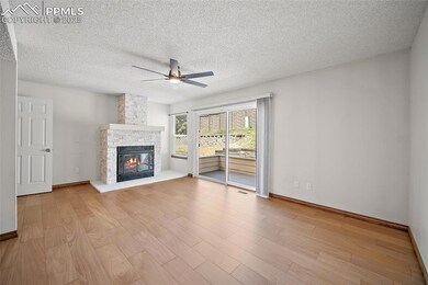 Unfurnished living room featuring a textured ceiling, light wood-style floors, a fireplace, and a ceiling fan