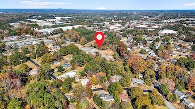 Aerial view of property's location featuring a tree filled landscape and nearby suburban area