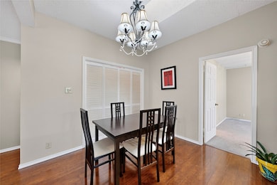Dining space with wood-like finished floors, a textured ceiling & a chandelier. The Utility Area is located in the closet in the dining area.