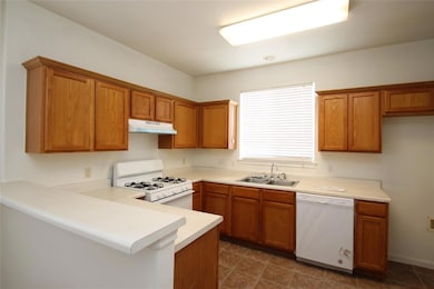 Kitchen featuring white appliances, a sink, under