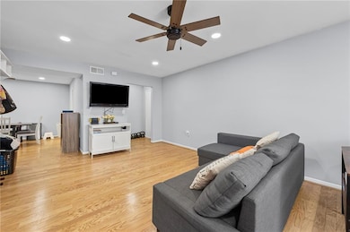 Living room with a ceiling fan, baseboards, recessed lighting, and light wood-style floors