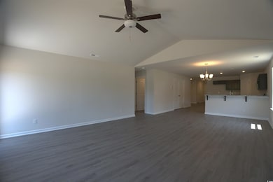 Unfurnished living room featuring a chandelier, vaulted ceiling, a ceiling fan, and dark wood finished floors
