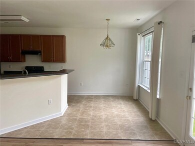 Kitchen with light wood-type flooring, black range oven, decorative light fixtures, and an inviting chandelier