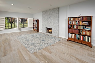 The expansive formal living room is bathed in natural light from a multitude of windows and is further highlighted by soaring 10 foot high ceilings, recessed lighting, elegant plantation shutters, a dramatic floor-to-ceiling gas burning fireplace and