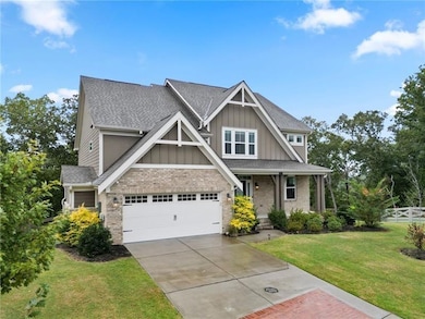 Craftsman inspired home with board and batten siding, brick siding, covered porch, a garage, and driveway