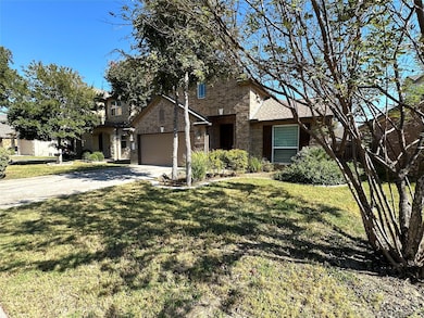 Traditional-style home with brick siding, driveway, a front lawn, and an attached garage
