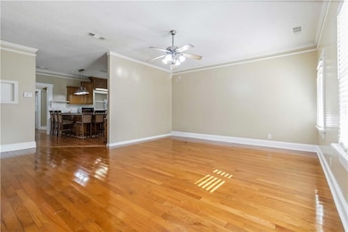 Unfurnished living room featuring crown molding, light wood-style flooring, ceiling fan, and a textured ceiling