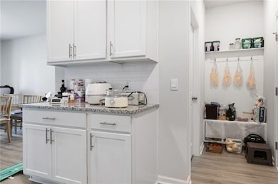 Bar featuring baseboards, tasteful backsplash, and light wood-type flooring