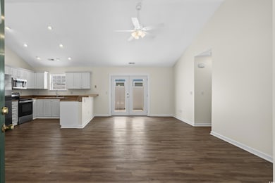 Kitchen featuring appliances with stainless steel finishes, lofted ceiling, a sink, ceiling fan, and white cabinets