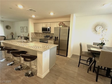 Kitchen with visible vents, backsplash, a breakfas