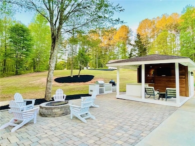 View of patio featuring an outdoor fire pit, grilling area, and view of wooded area
