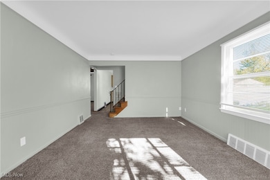 Carpeted spare room with stairway and a wainscoted wall