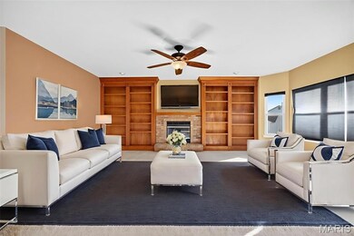 Living room featuring a fireplace, built in shelves, and ceiling fan