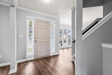 Entryway featuring a textured ceiling, dark wood f