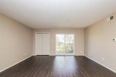 Unfurnished bedroom with dark wood-style floors, a closet, a textured ceiling, and access to exterior