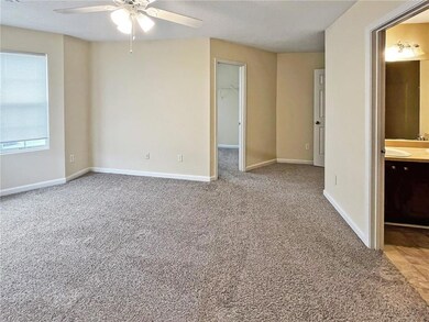 Carpeted empty room featuring ceiling fan and baseboards