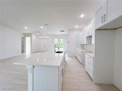 Kitchen with a kitchen island with sink, white cab